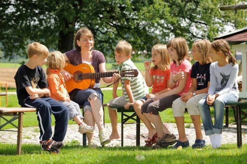 Kinder-Gitarre-singen-urlaub-auf-dem-bauernhof-am-chiemsee-chiemgau-luxus-ferienbauernhof-unterkunft-ferienwohnung-kinderfreundlich-mit-frühstück-mit-pferden-reiten-moierhof