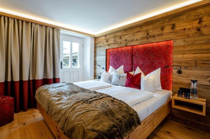 Schlafzimmer-mit-Altholz-Täfelung-hinter-Bett-urlaub-auf-dem-bauernhof-am-chiemsee-chiemgau-luxus-ferienbauernhof-unterkunft-ferienwohnung-kinderfreundlich-mit-frühstück-reiten-moierhof