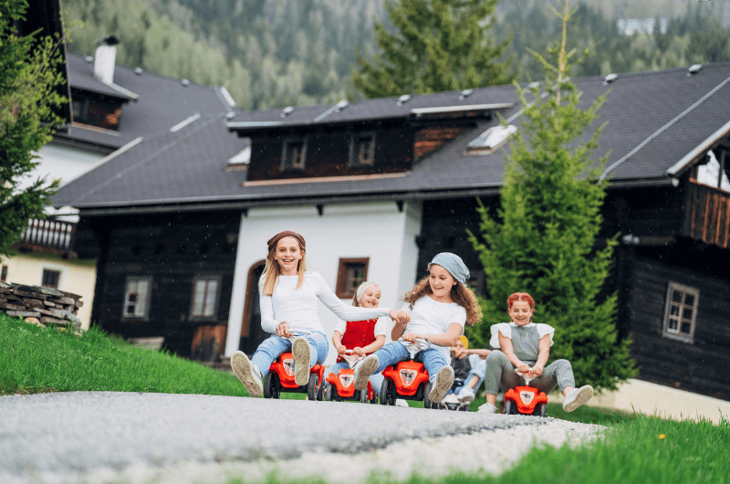 Huettendorf-Feriendorf-Oesterreich-Urlaub-mit-Kind-Skiurlaub-Ferienwohnung-Kaernten-Slow-Travel-Resort-Kirchleitn-nachhaltig-Bobbycars